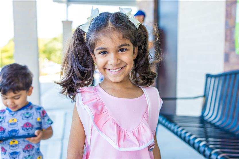 A girl wearing a pink shirt smiles